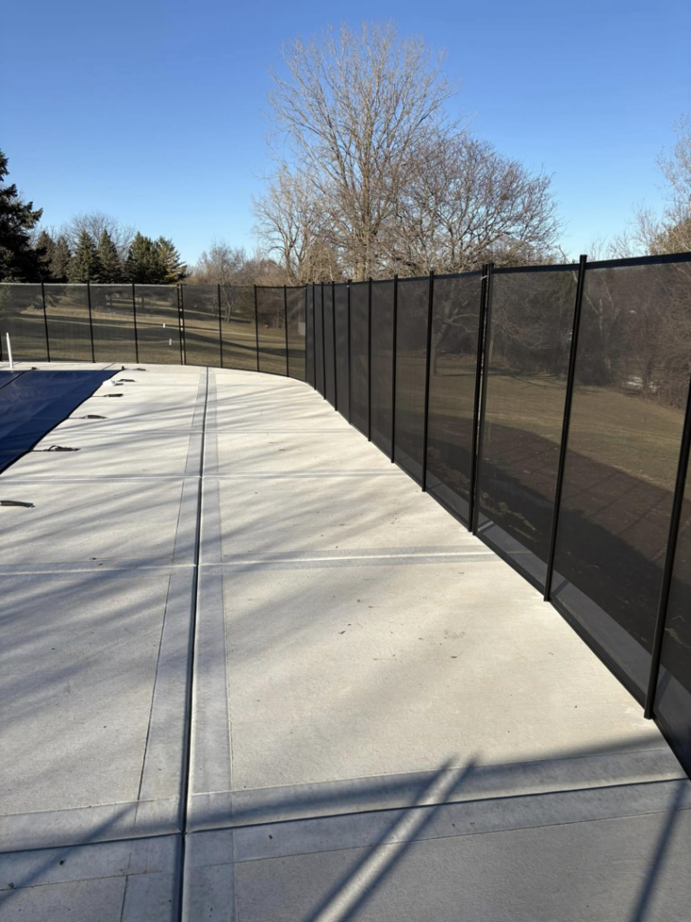 A newly installed black mesh pool safety fence around a residential pool by Safe Yard Fence - Waukesha County in Waukesha, WI.