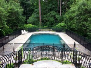 A black mesh pool safety fence installed around a swimming pool by Sumter Fence Company in South Sumter, SC.