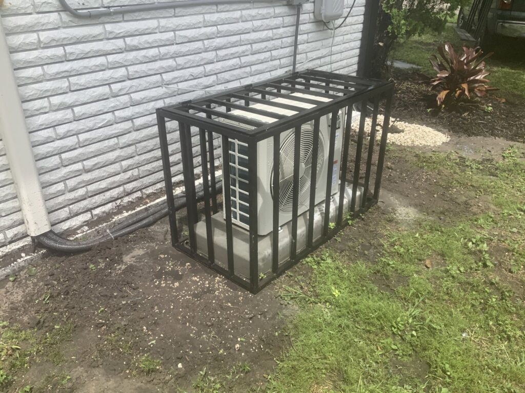 Black metal security cage installed around an outdoor AC unit by Ability Burglar Bars in Jacksonville, FL.