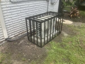 Black metal security cage installed around an outdoor AC unit by Ability Burglar Bars in Jacksonville, FL.