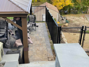 A combination of black metal and chain-link fencing installed around a patio area by David Platania Fence in Derry, NH.