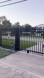 An automatic black metal sliding gate with an opener for property access by ARE FENCE LLC in Miami, FL.