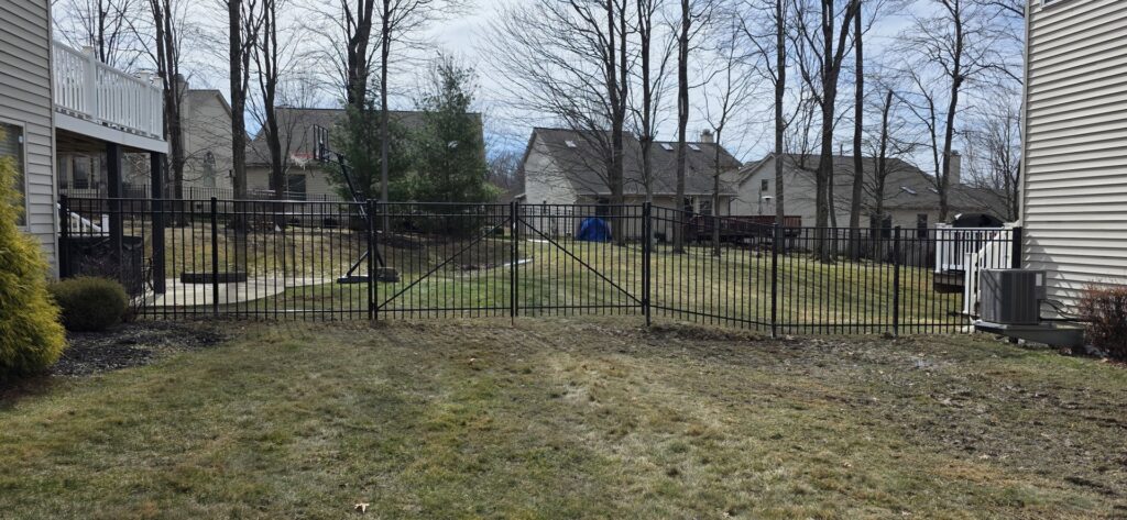 A black metal fence installed in a residential backyard by Affordable Fencing in Parma, OH.