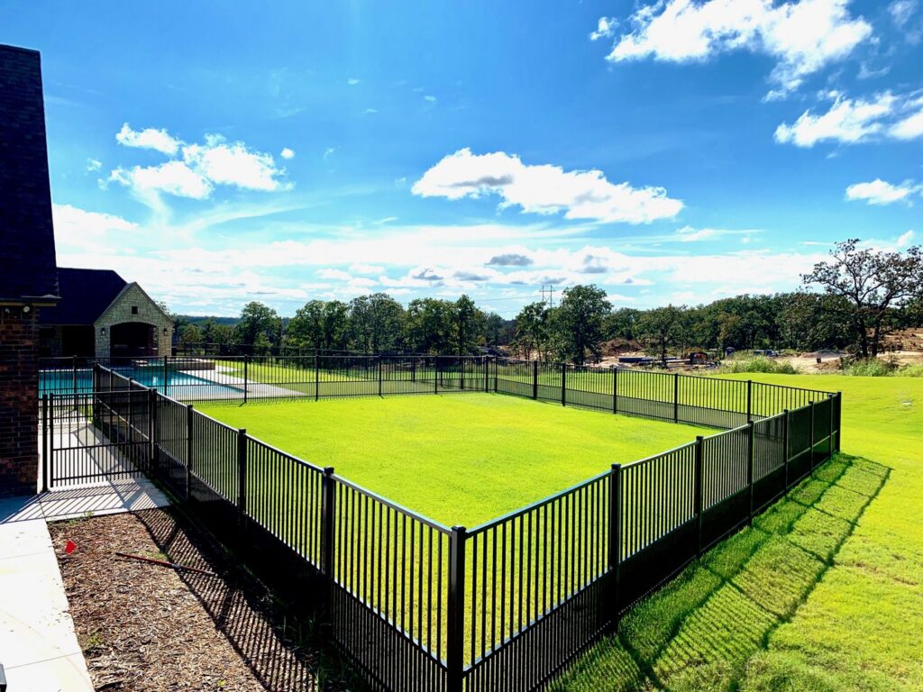 A corner section of a black metal backyard fence installed by Ninety-One Services, providing security in Tulsa, OK