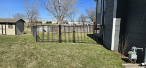 A modern black metal fence installed in a residential backyard by ICT Fence in Wichita, KS.