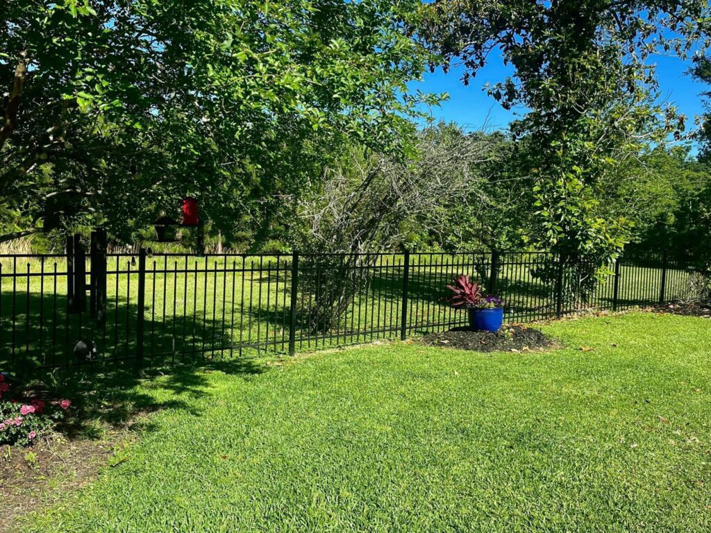 A decorative black metal fence enclosing a residential backyard, installed by JH Fencing in Lawrence, KS.
