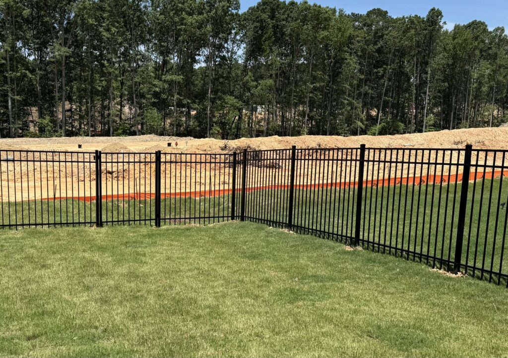A black metal fence installed around a backyard in a new construction area by Align Fence Builders in Durham, NC.