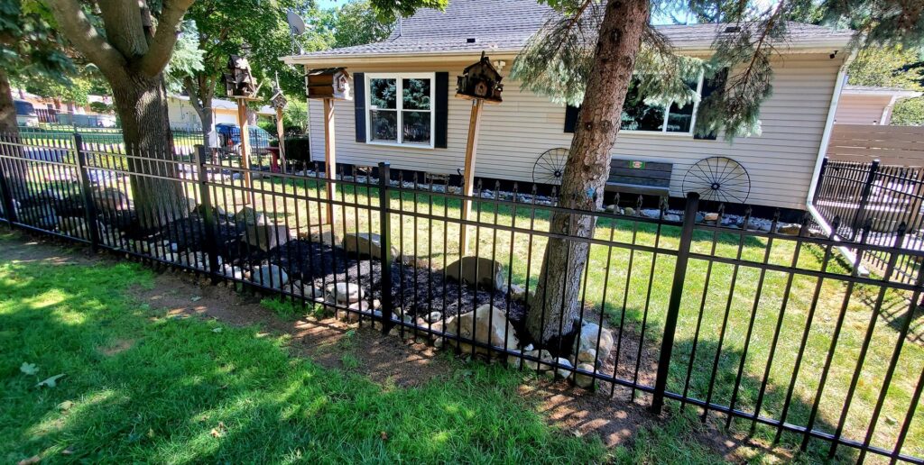 A sleek black metal fence installed in a residential backyard, enhancing security and aesthetics, by Sparta Fencing in Ely, UK.