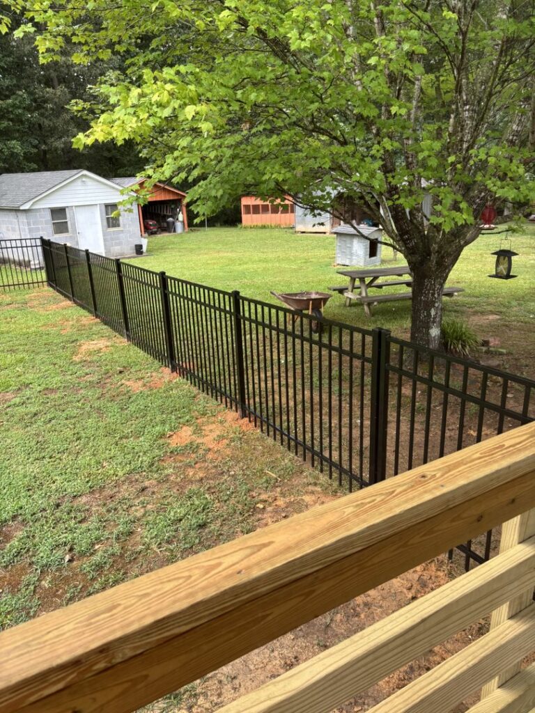Durable black metal fence installed in a spacious backyard by Sunrise Fences, offering elegant security in Goose Creek, SC.