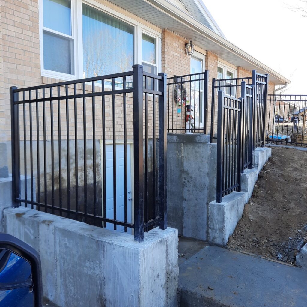 Black metal railings installed around a basement entrance and window well by James Fencing LLC in Columbia, MO.
