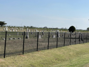 A black metal fence installed along the border of a cemetery by Fence Restorations LLC in Ponca City, OK.