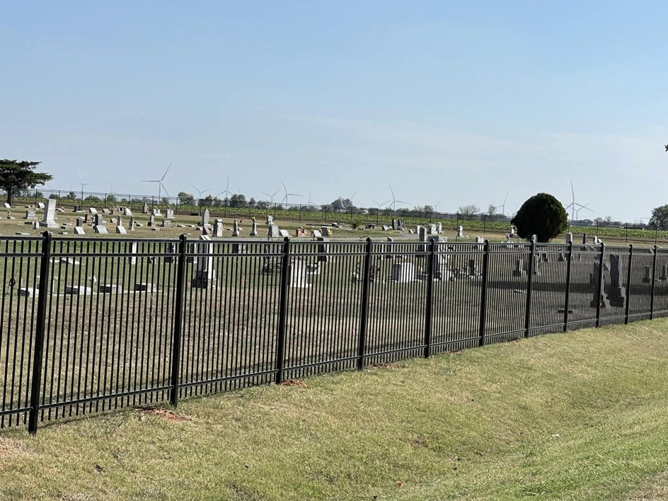 A black metal fence installed along the border of a cemetery by Fence Restorations LLC in Ponca City, OK.