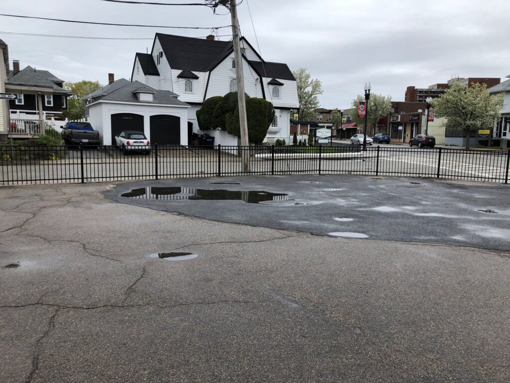 A black metal commercial fence enclosing a parking lot area by OMA Fence,LLC in Weymouth, MA