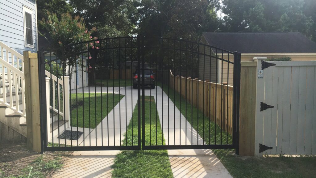 A new black metal double gate installed at a residential driveway entrance by Charleston Fencing Services in Moncks Corner, SC.
