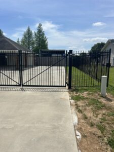 A black metal driveway gate and fence installed by A-1 Security Fence in Scott, LA.