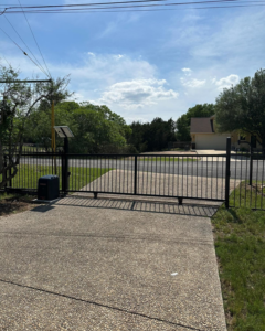 A newly installed black metal double driveway gate with a solar-powered opener by Down South Welding and Fabrication in Canyon Lake, TX.