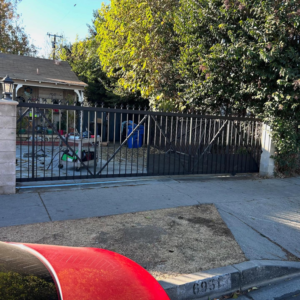 A newly installed black metal driveway gate with decorative spikes by Rossi Welding Metal in Los Angeles, CA.