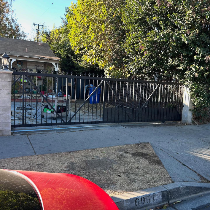 A newly installed black metal driveway gate with decorative spikes by Rossi Welding Metal in Los Angeles, CA.