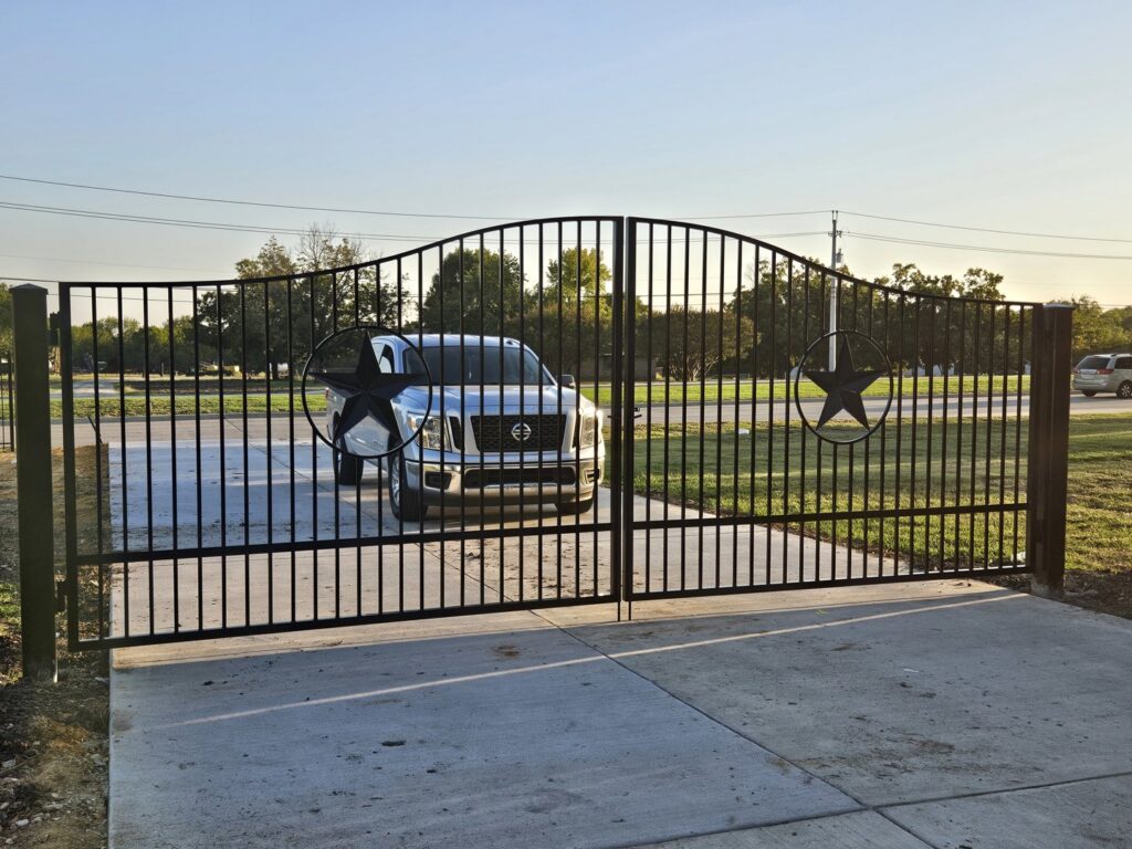 A large black metal driveway gate featuring decorative Texas star accents, installed by QD & E Fencing in Fort Worth, TX.