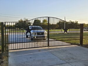 A large black metal driveway gate featuring decorative Texas star accents, installed by QD & E Fencing in Fort Worth, TX.