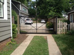 A black metal driveway gate with an adjacent wooden fence section installed by Timber Fencing in Charlotte, NC.
