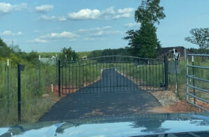 A black metal entry gate at the end of a paved driveway installed by United Fence Company in Johnston, RI.