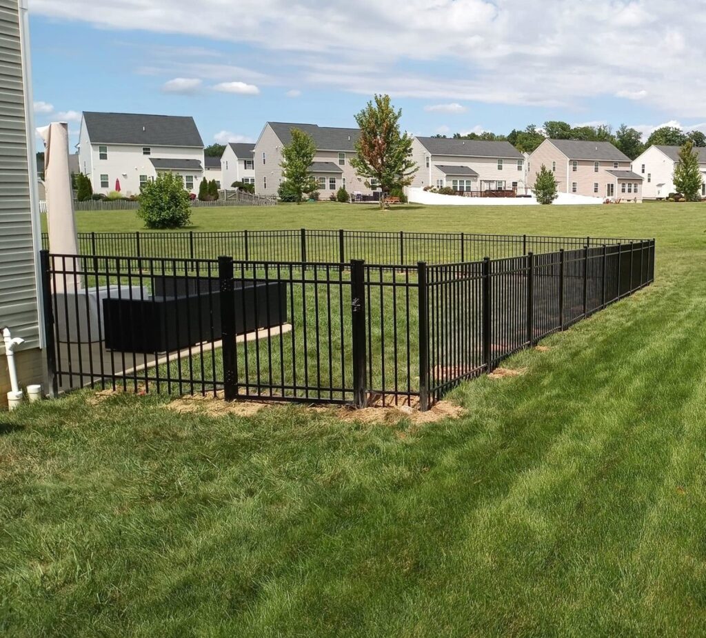 A black metal fence enclosing an outdoor AC unit in a backyard by Affordable Fencing in Parma, OH.