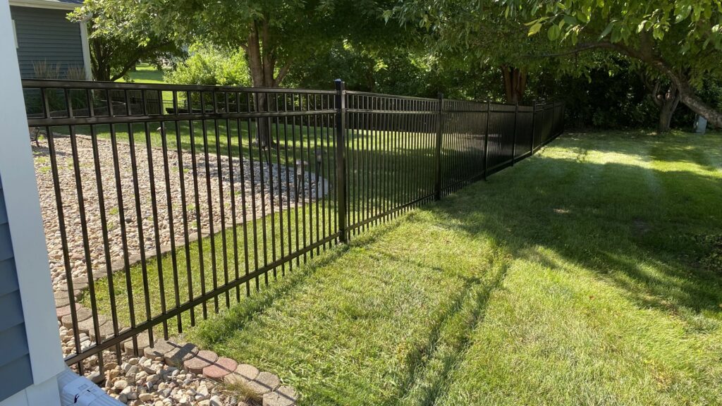 A durable black metal fence installed along a residential property line by Thrive Fencing in Ames, IA.