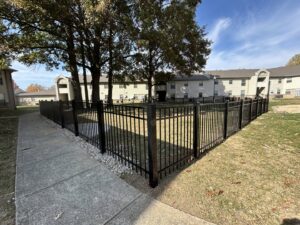 A black metal fence enclosing a grassy area next to an apartment complex by Morton Fence Solutions LLC in Indianapolis, IN.
