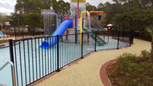 A black metal fence installed around a community pool and splash pad by Best Fence and Rail in Jacksonville, FL.