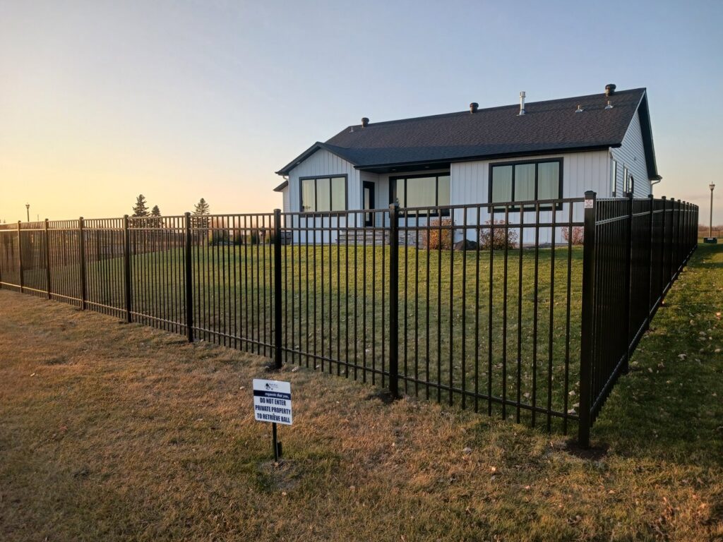 A black metal fence installed around a modern house by Aces Deck and Fence, LLC in Fargo, ND.