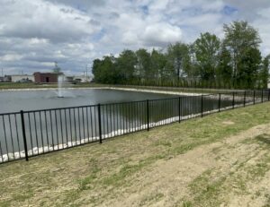 A durable black metal fence installed around a pond, providing safety and elegance by 985 Fence, LLC in Schriever, LA.