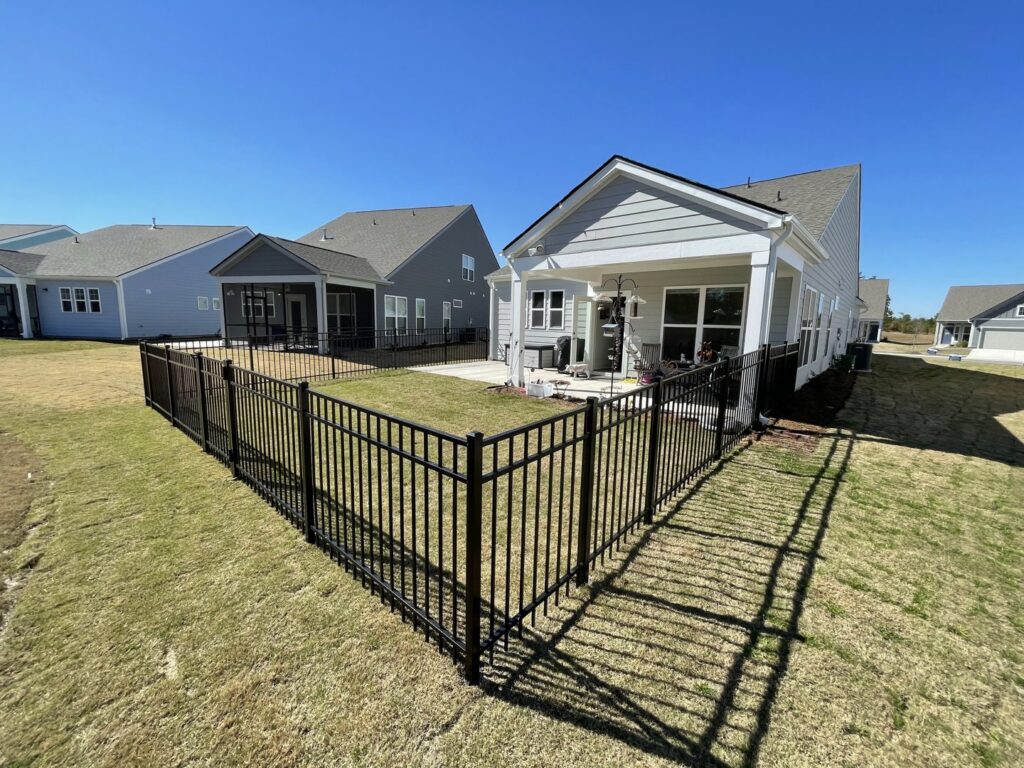 A newly installed black metal fence enclosing a backyard patio area by Charleston Fencing Services in Moncks Corner, SC.
