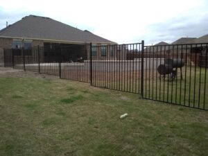 A black metal fence enclosing a backyard with a swimming pool and patio by Landmark Fence & Deck Company in Saint Paul, MN.