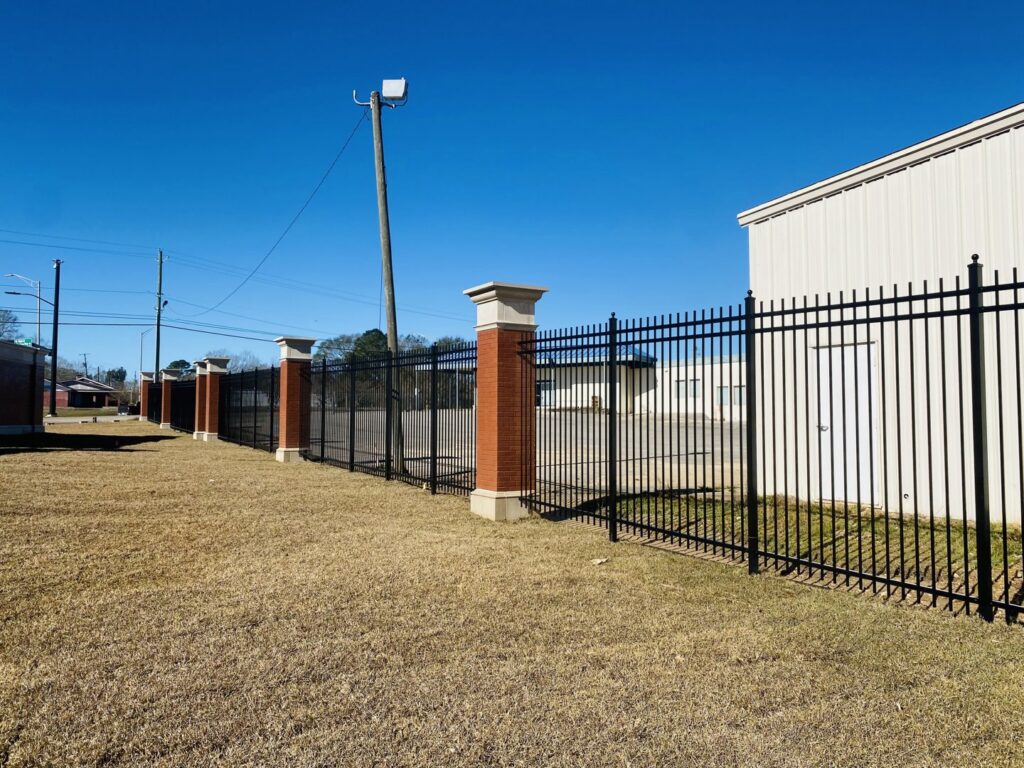 A black metal fence with decorative brick pillars installed for a commercial property by Jefcoat Fence Co. Inc. of Hattiesburg, MS