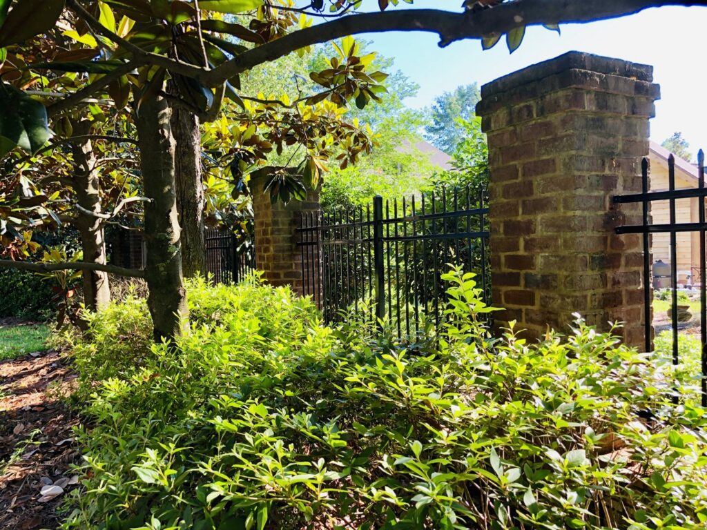 A black metal fence with brick pillars installed for a residential property by Jefcoat Fence Co. Inc. of Hattiesburg, MS
