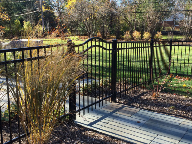 A black metal fence featuring a decorative arched gate installed by Freeman Fence in Atlanta, GA.