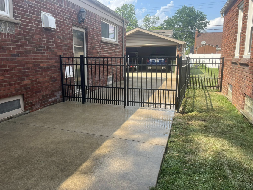 A black metal fence with a double gate installed next to a house by Final Touch Fencing LLC in Macomb Township, MI.