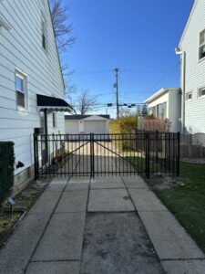 A black metal fence with a double gate installed across a residential driveway by Affordable Fencing in Parma, OH.