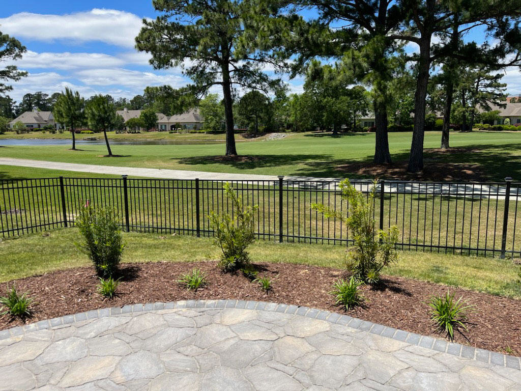 A black metal fence bordering a golf course, installed by Heavenly Gates Construction LLC in Miami, FL