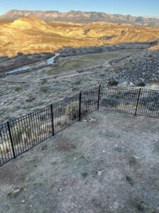 A black metal fence installed on a hillside, offering a scenic view, by Legacy Fencing LLC in St. George, UT.