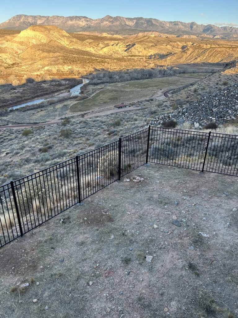 A black metal fence installed on a hillside, offering a scenic view, by Legacy Fencing LLC in St. George, UT.