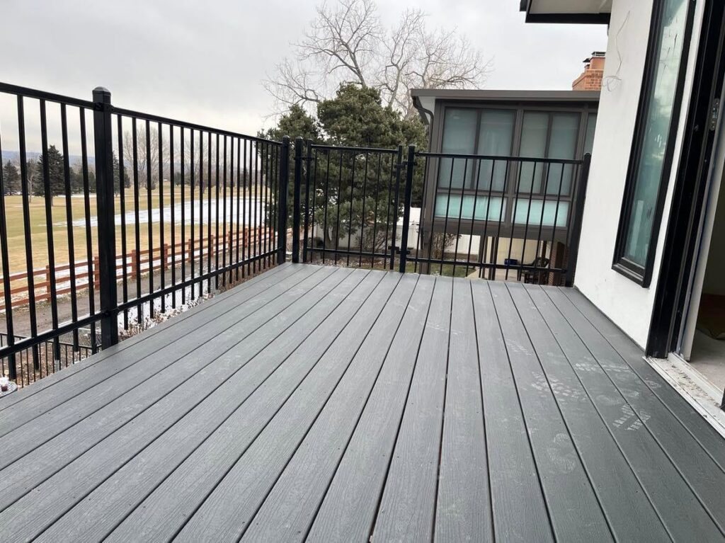 A black metal fence with a gate providing a secure perimeter and a scenic lake view by Supreme Fencing Denver, CO.