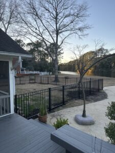 A black metal fence installed along the edge of a lake or pond, viewed from a residential deck by Five Star Fence in Charleston, SC.