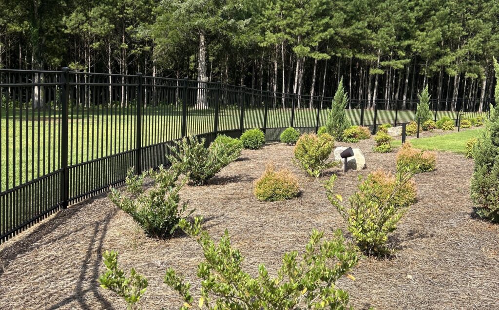 A black metal fence bordering a landscaped area by Creative Fence Designs in Columbus, GA.