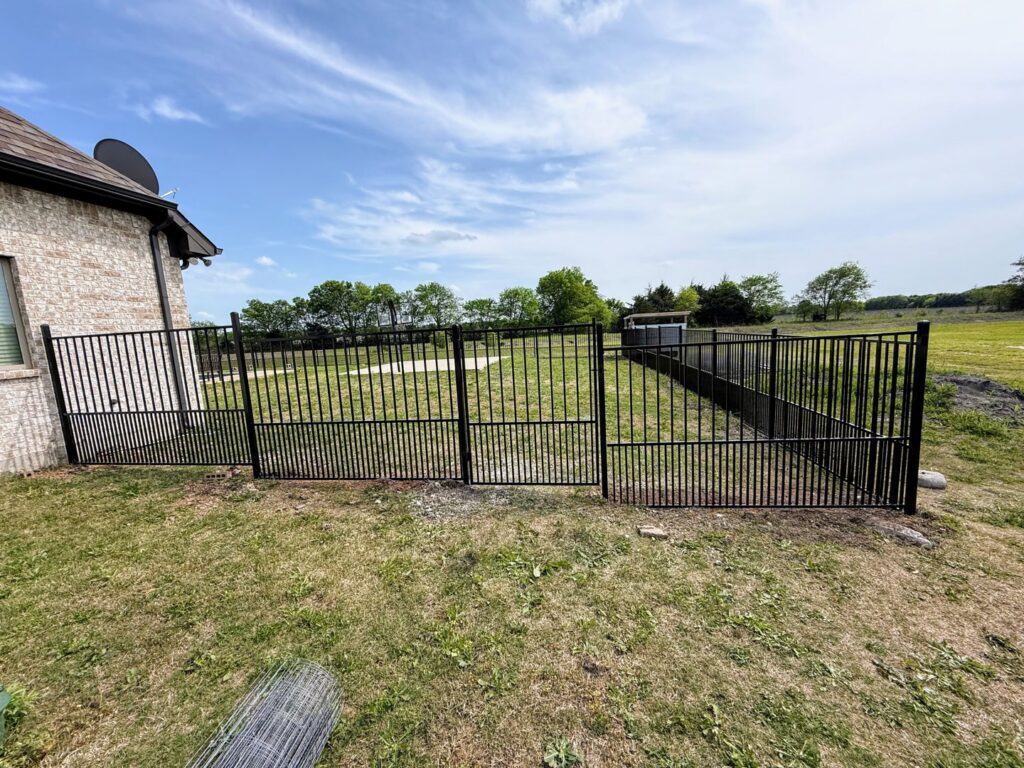 A sturdy black metal fence enclosing a large grassy area, installed by Stand Strong Fencing of Plano, TX