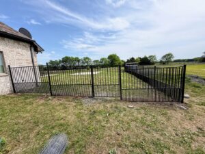 A sturdy black metal fence enclosing a large grassy area, installed by Stand Strong Fencing of Plano, TX