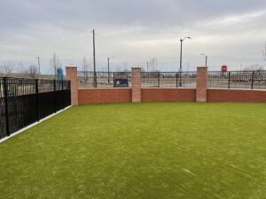 A black metal fence installed on a decorative brick wall around an artificial turf area by The Fence Man in Fort Smith, AR