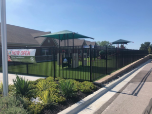 A black metal fence enclosing a playground area, installed by Mann Fence Co., Inc. in Olathe, KS.