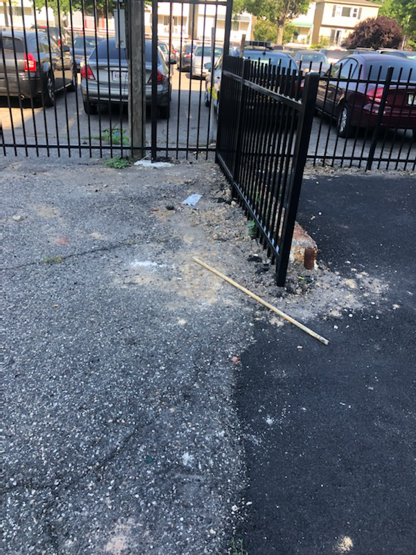 A close-up view of a black metal fence post during an installation or repair by Fox Fence Enterprises Inc in Clifton, NJ.
